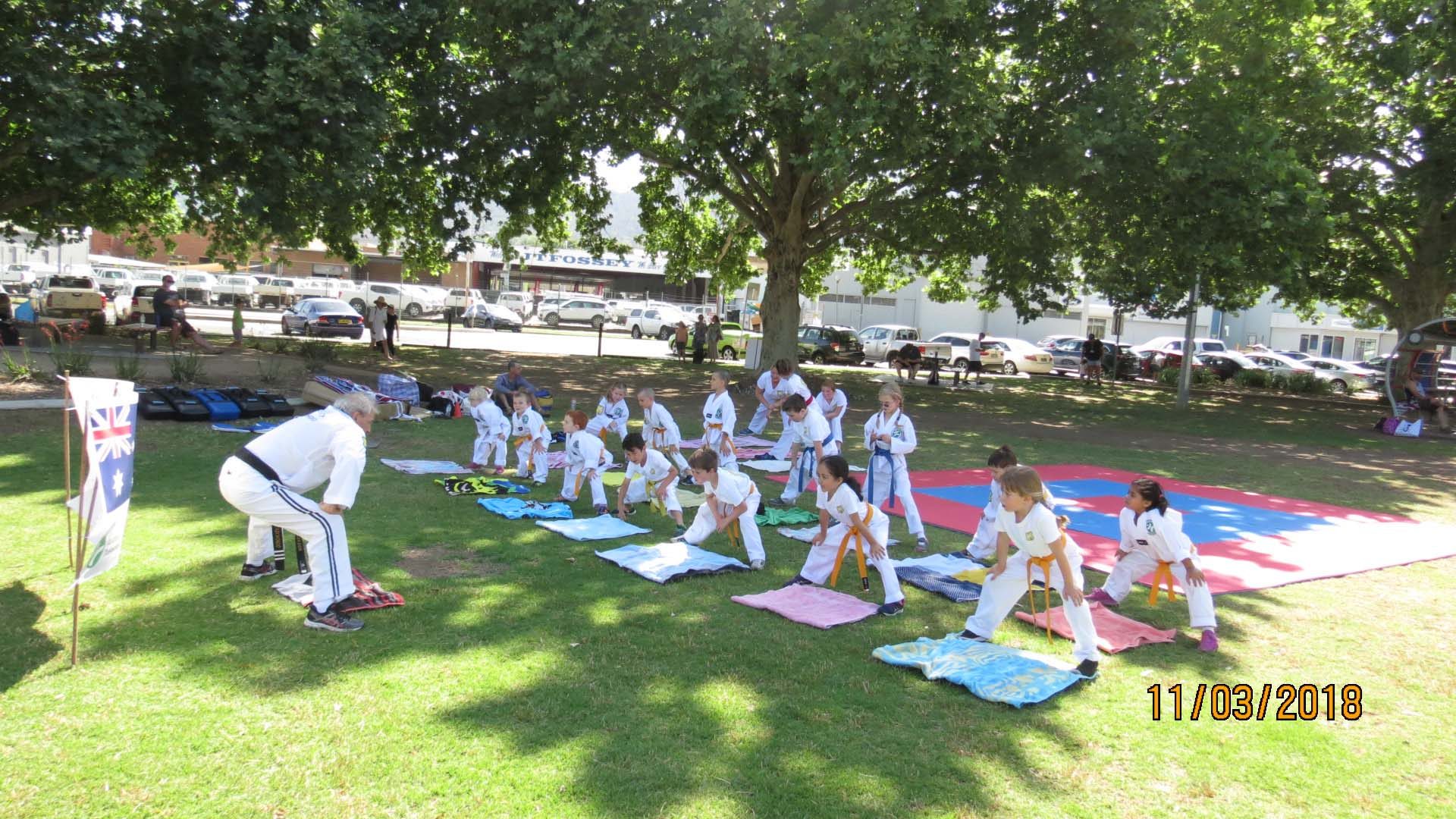 Young students preparing to practice the martial art of taekwondo in a park in Tamworth.